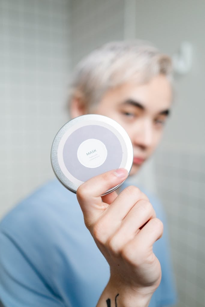 Man Holding A Cosmetic Mask In Round Container